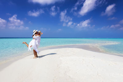 Full length of couple embracing on beach against sky