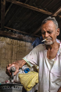 Mature man smoking cigarette while ironing