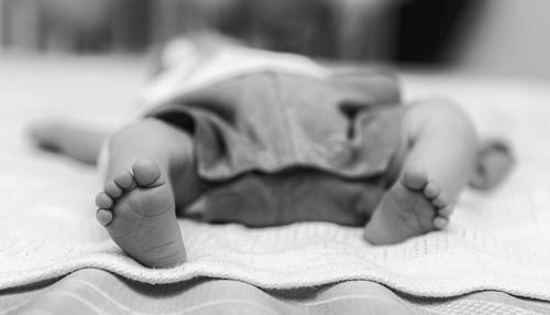 Low section of baby boy lying on bed