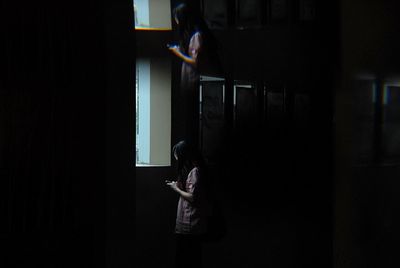 Side view of girl standing against window at home