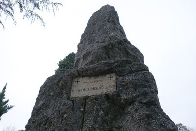 Low angle view of text on rock against sky