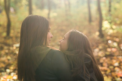 Side view of young woman against trees