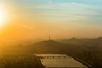 Silhouette bridge over river against sky during sunset