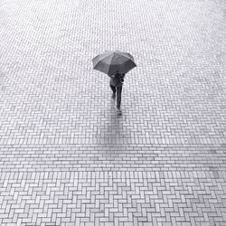 High angle view of man walking with umbrella on walkway