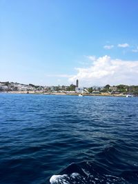 Distant view of city by sea against sky