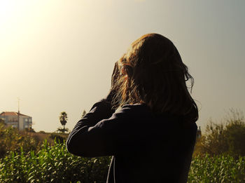 Rear view of girl standing against sky during sunset