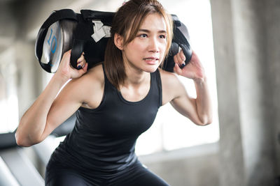 Low angle view of young woman lifting weights in gym