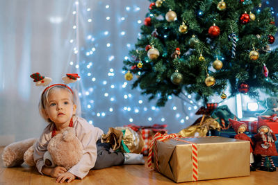 Cute girl decorating christmas tree at home