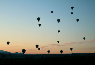 Hot air balloons flying against sky during sunset