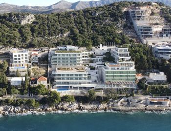 Buildings by sea against trees