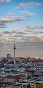 Aerial view of buildings in city against cloudy sky