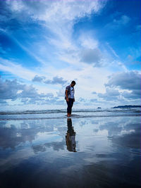 Full length of boy standing on beach against sky