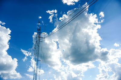 Low angle view of electricity pylon against blue sky