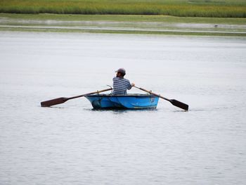 Rear view of man sitting on boat in water