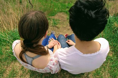 Rear view of woman and man sitting on grass