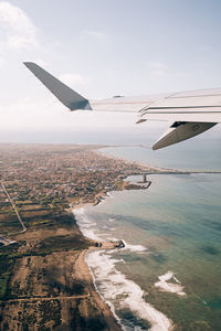 Aerial view of airplane flying over landscape against sky