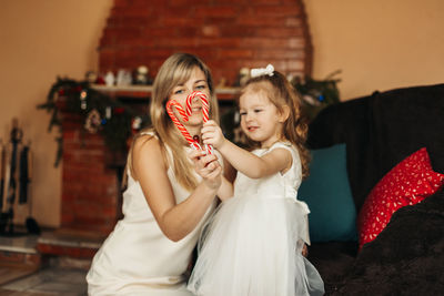 Close-up of a heart made of christmas lollipops in the hands of a mother and daughter