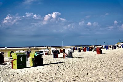 Hooded chairs on beach against sky