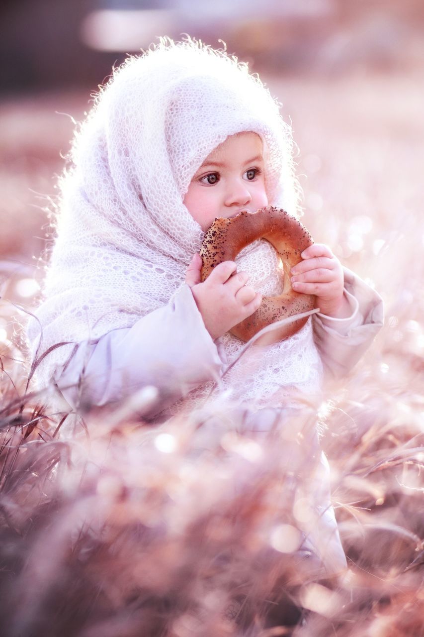 one person, winter, warm clothing, cold temperature, portrait, selective focus, lifestyles, real people, snow, clothing, leisure activity, holding, women, looking at camera, females, girls, hat, childhood, innocence, outdoors, softness