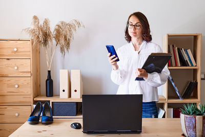 Brunette woman uses mobile phone while working in the office. remote working concept
