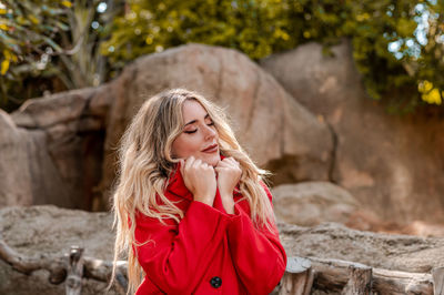 Portrait of young woman standing against rock