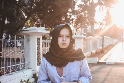 Portrait of young woman in hijab standing against trees