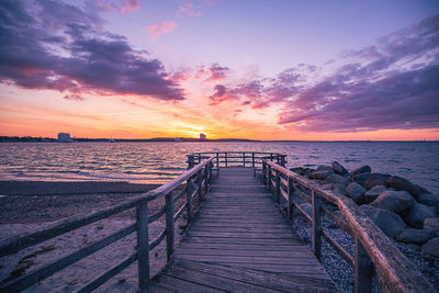 Pier over sea against sky during sunset