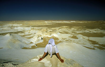 Rear view of man sitting on rock 