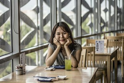 Portrait of young woman sitting on table at restaurant