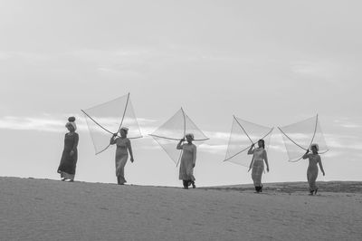 People working by sea against sky