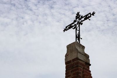 Low angle view of weather vane against sky