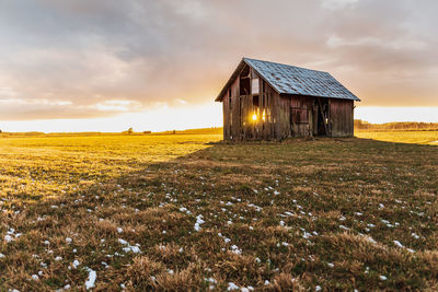 Old barn on arable land  that keeps falling apart with a sunset that radiates through the house 