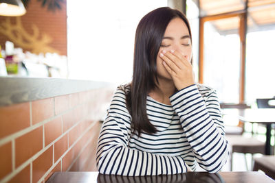 Young woman yawning at restaurant