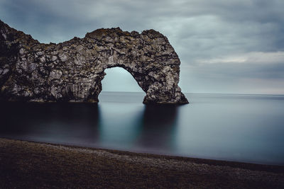 Rock formation in sea against sky