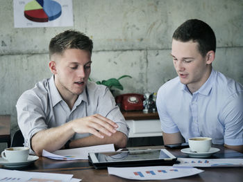 Colleagues discussing over digital tablet in office