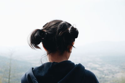 Rear view of woman looking at mountains against clear sky