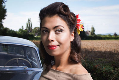 Close-up of smiling woman by vintage car against sky