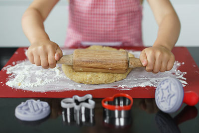 Young girl cooking delicious cookies in her kitchen. child rolling the dough uit .