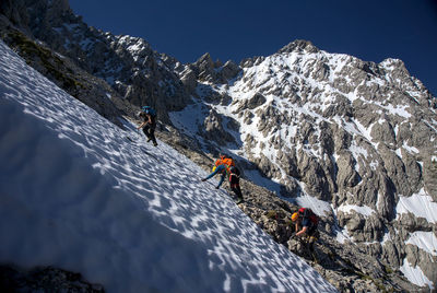 People on snowcapped mountain against sky