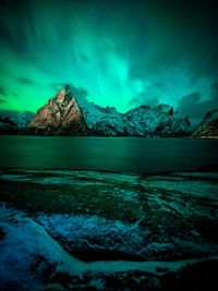Scenic view of aurora borealis over sea against sky at night