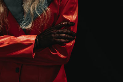 Part of a female body dressed in an creative red leather jacket and black mesh glove.