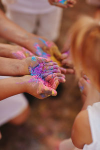 Hands of children and adults in the colors of the hall. family having fun with holi paints outdoors