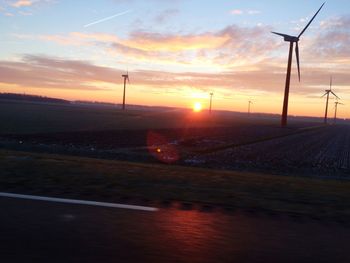 Windmill on field against sky during sunset