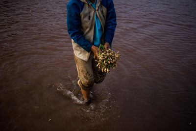 Low section of man standing in river