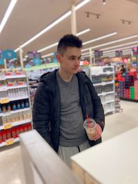 Young man looking away while standing at store