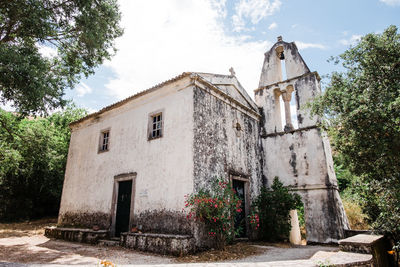 Exterior of old building by trees against sky