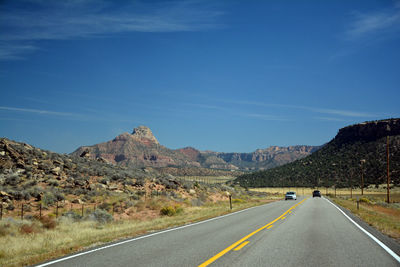 Road passing through mountains against blue sky