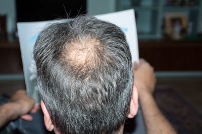 Rear view of man reading paper