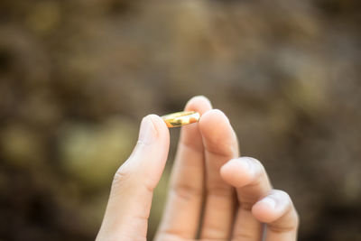 Close-up of hand holding cigarette against blurred background