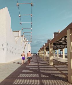 Rear view of shirtless men walking by building